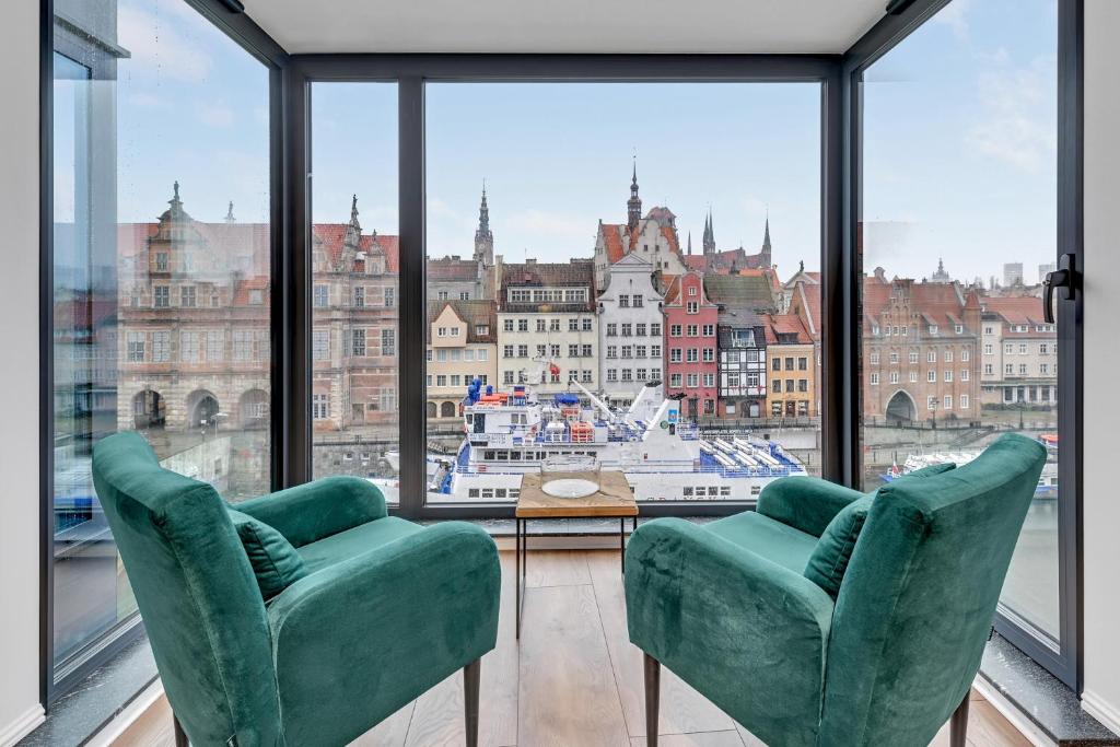 a room with two green chairs and a large window at Deo Plaza by Blue Mandarin in Gdańsk