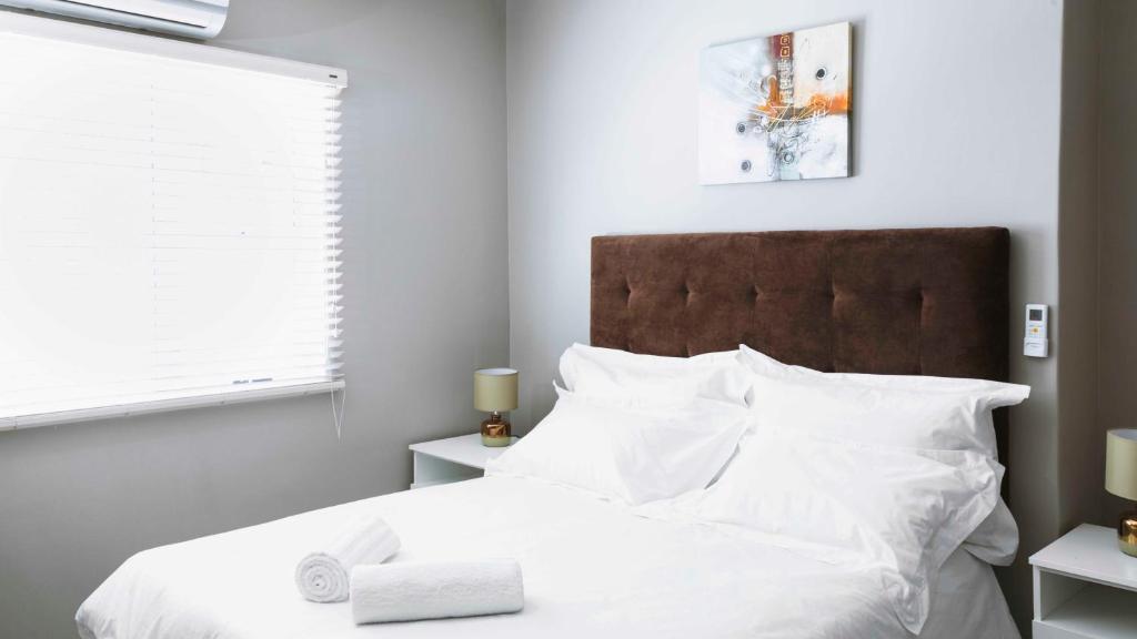 Un dormitorio con una cama blanca con almohadas blancas. en 103onWallace Self Catering Guest House, en Ciudad del Cabo