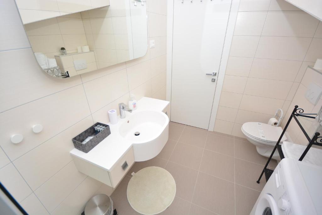 biała łazienka z umywalką i lustrem w obiekcie Apartment 3 with the private jacuzzi w mieście Turanj