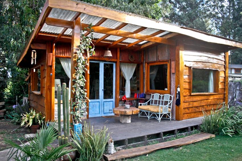 Cabaña de madera pequeña con porche y mesa en Bosque Peralta Ramos Cabañas Nalu 1 en Mar del Plata