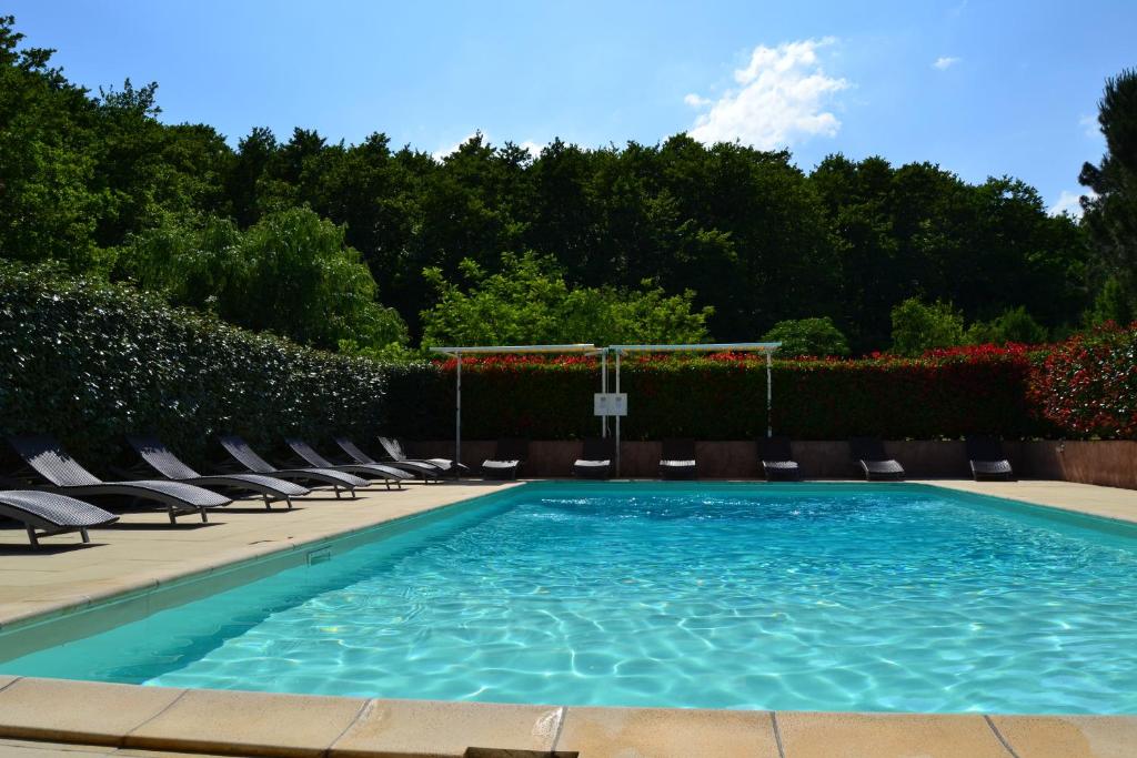 - une piscine avec des chaises longues à côté d'une haie dans l'établissement Résidence Les Aulnes, à Porto-Vecchio