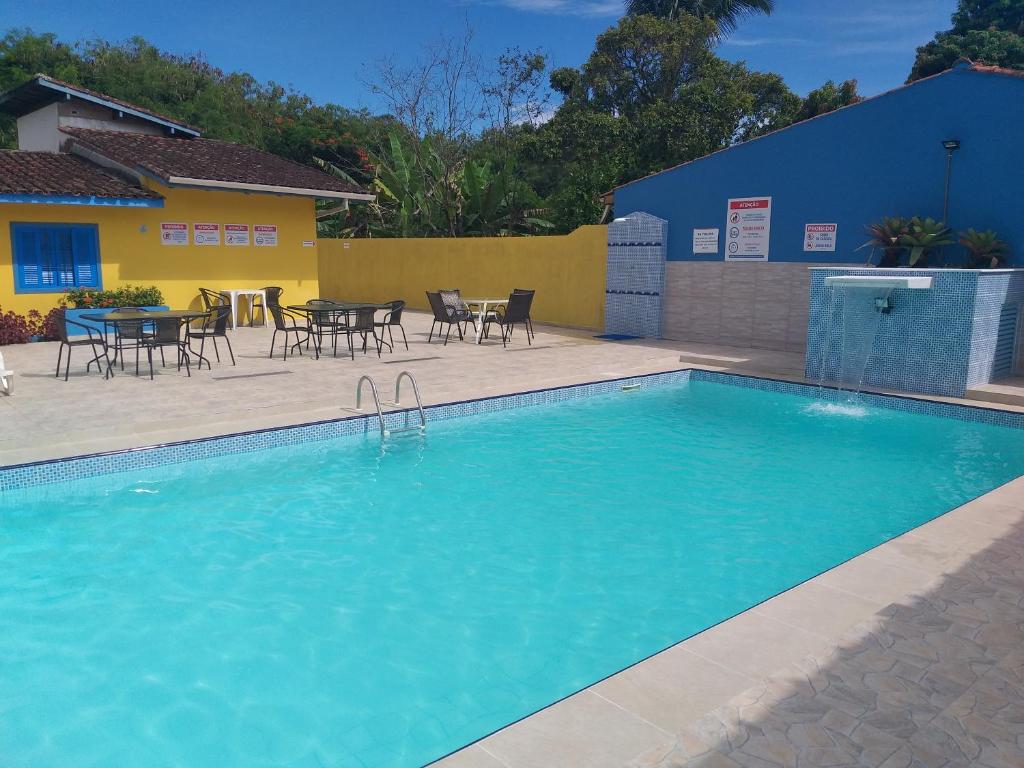 uma piscina com cadeiras e uma mesa em frente a um edifício em Pousada da Costa em Caraguatatuba