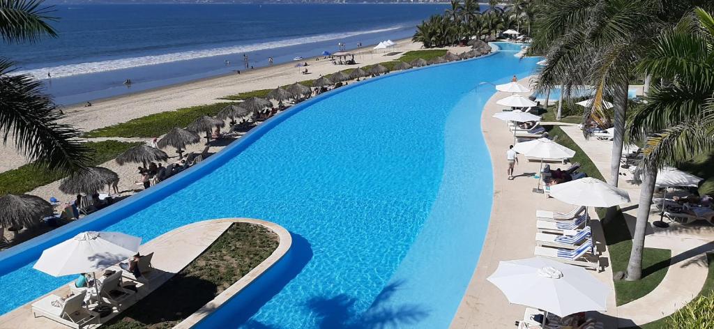 una piscina con sombrillas y una playa en Peninsula Nuevo Vallarta, en Nuevo Vallarta 