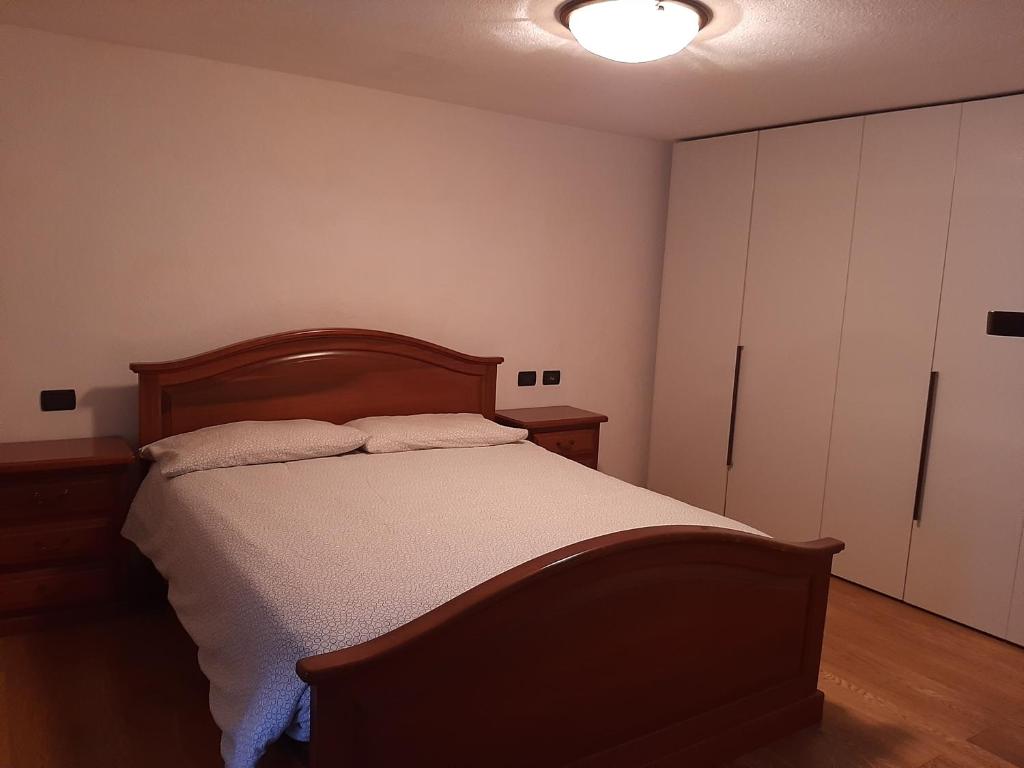 1 dormitorio con 1 cama con cabecero de madera y armarios blancos en La Tanière, en Morgex