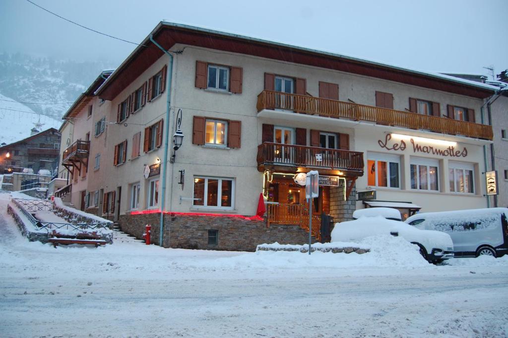 een groot gebouw in de sneeuw met auto's geparkeerd voor bij Appartements avec draps inclus dans le tarif in Lanslebourg-Mont-Cenis