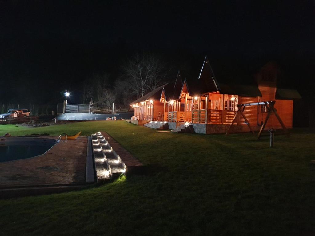 una cabaña de madera por la noche con luces encendidas en Imperator Kvintil apartmani & SPA, en Ležimir