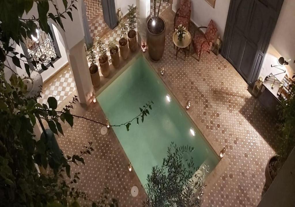 a pool of water on a tiled floor with potted plants at Riad Magellan Yoga and Spa in Marrakesh