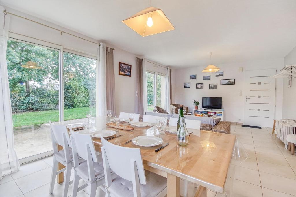 comedor con mesa de madera y sillas blancas en Iroise, en Lamballe