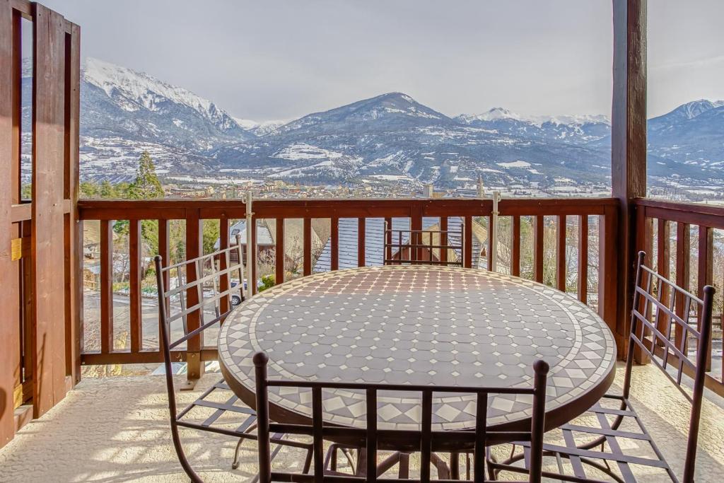 einen Tisch auf dem Balkon mit Bergblick in der Unterkunft Les Fauvettes - appartement vue imprenable sur montagne in Embrun