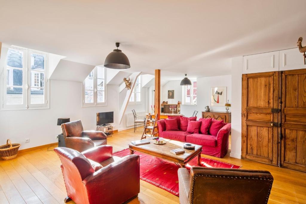 ein Wohnzimmer mit einem roten Sofa und Stühlen in der Unterkunft Sotto Le Stelle - Fabuleux duplex d'hyper centre in Rennes