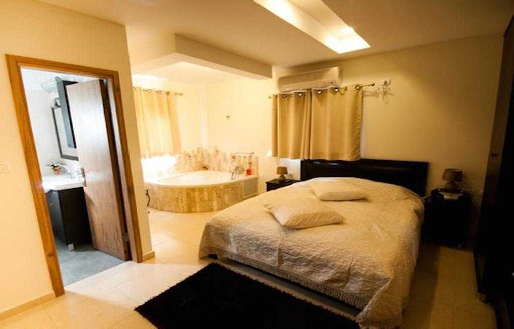a bedroom with a bed and a bath tub at Elimelech Bapardes in Sheʼar Yashuv