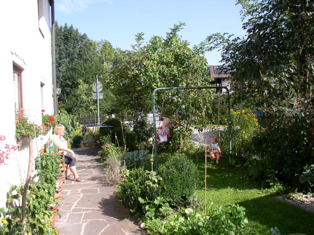 a woman sitting on a chair in a garden at Gästehaus Monalisa in Grabenstätt