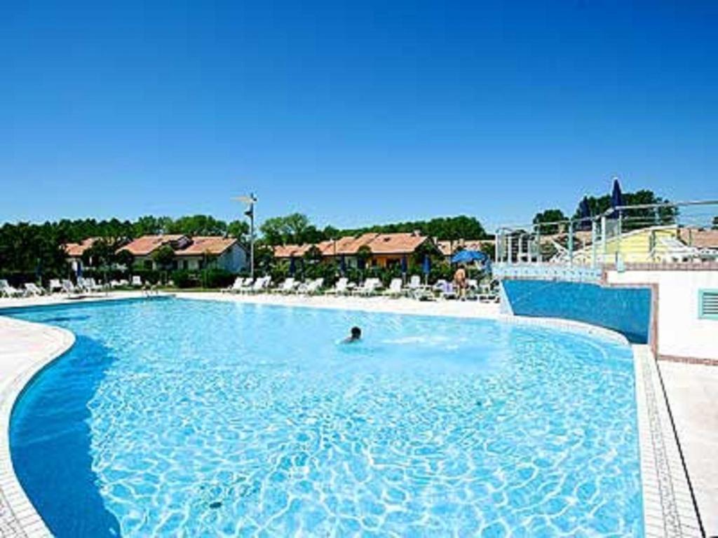 a person swimming in a large blue swimming pool at Casabianca Resort Villas in Lignano Sabbiadoro