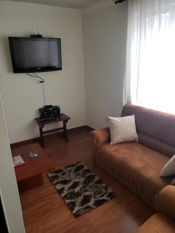 sala de estar con sofá y TV de pantalla plana en Apartamento confort centro, en Pasto