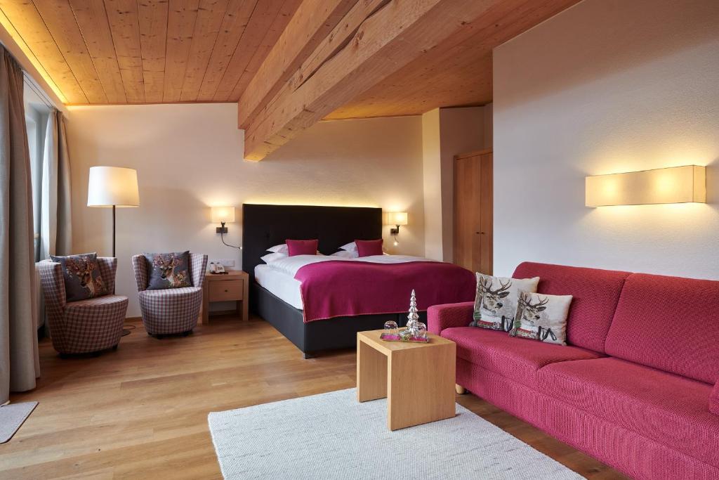 a bedroom with a bed and a red couch at Hotel Garni Schneider in Lech am Arlberg