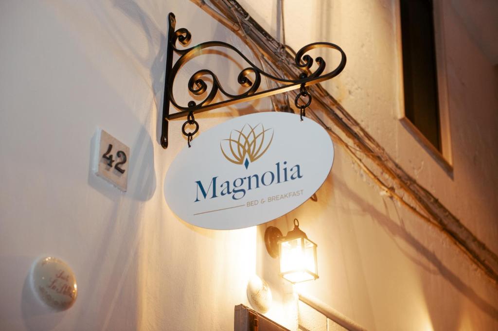 un cartello appeso a un muro con una luce di Magnolia a Grottaglie