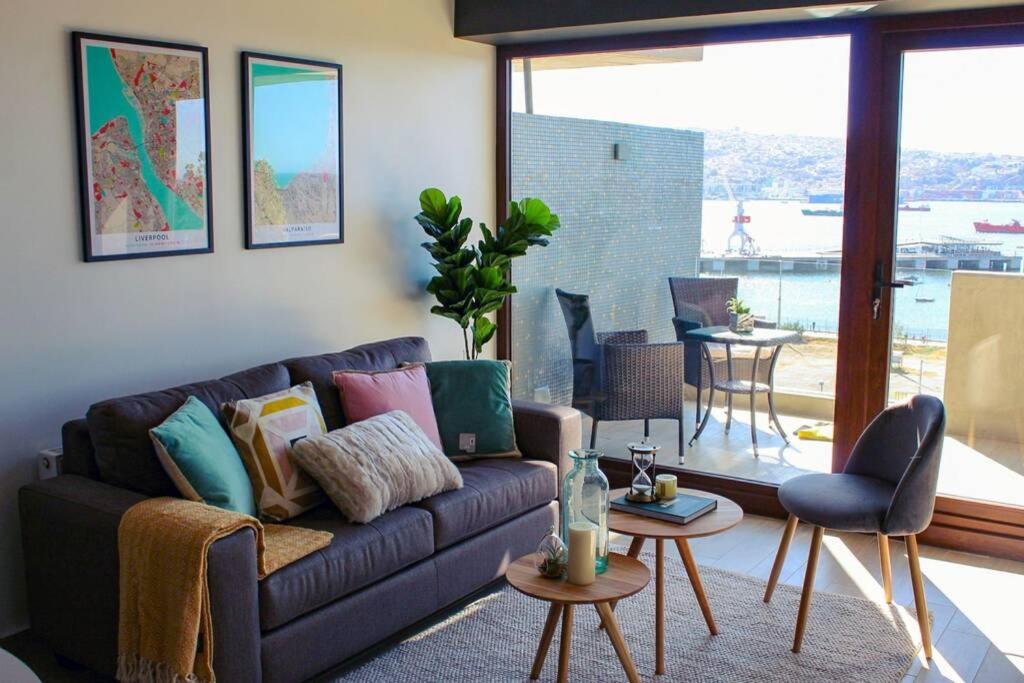 uma sala de estar com um sofá e uma grande janela em Espectacular departamento con vista al mar en Mirador Barón Valparaíso em Valparaíso