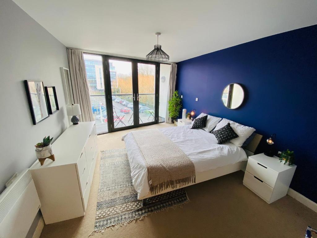 a blue bedroom with a bed and a large window at Stewart St James Walk Apartment in Cheltenham