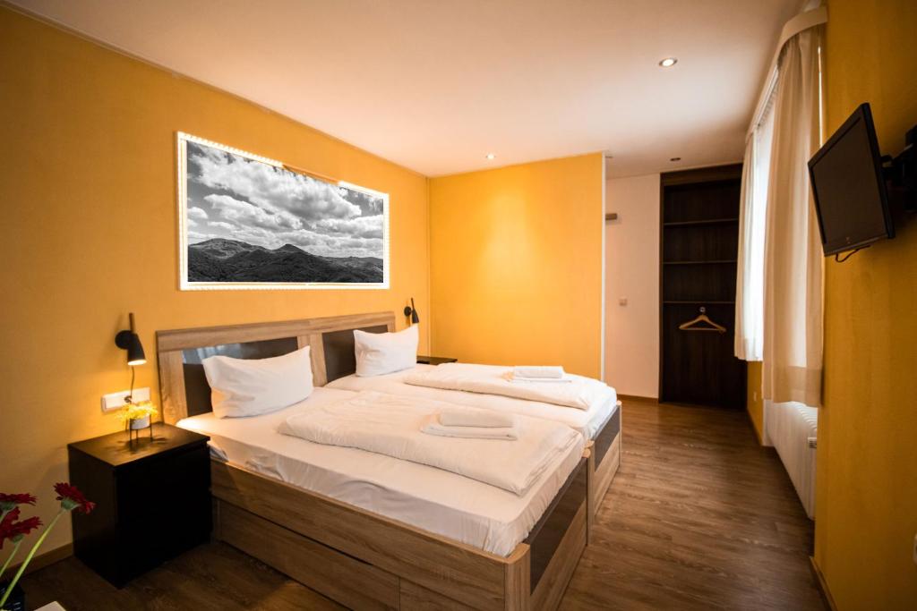 a bedroom with a large bed with white sheets at Hotel Stadtschänke in Walsrode