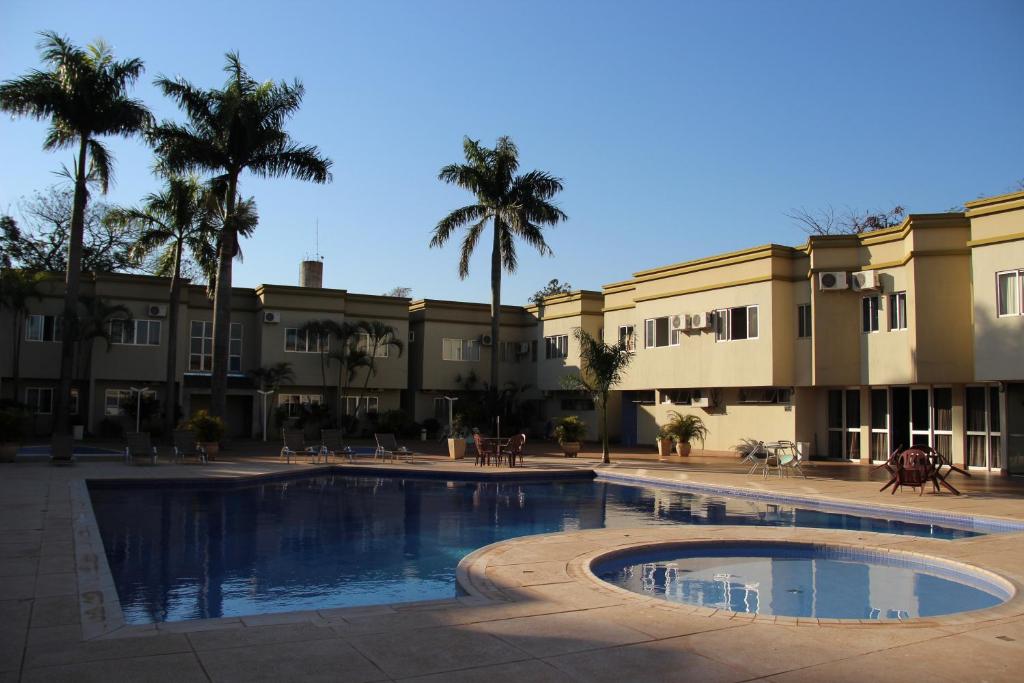 a pool in front of a building with palm trees at Muffato Plaza Hotel in Foz do Iguaçu