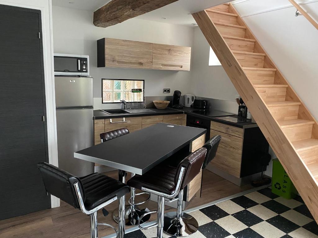 cottage Philippe et Valérie في Silly-en-Gouffern: مطبخ مع طاولة سوداء وبعض الكراسي