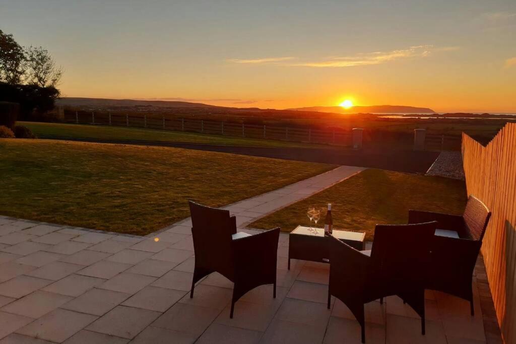 a patio with a table and chairs at sunset at Béal na Banna in Coleraine