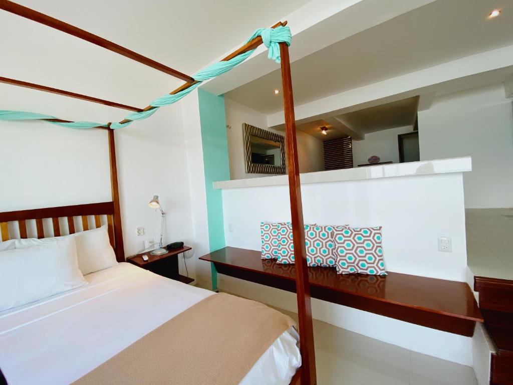 a bedroom with a canopy bed and a desk at Rocamar Hotel Isla Mujeres in Isla Mujeres