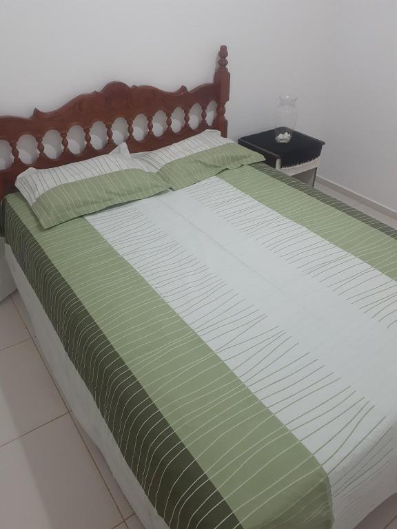 a large bed with a green and white comforter at Quarto em apartamento in Suzano