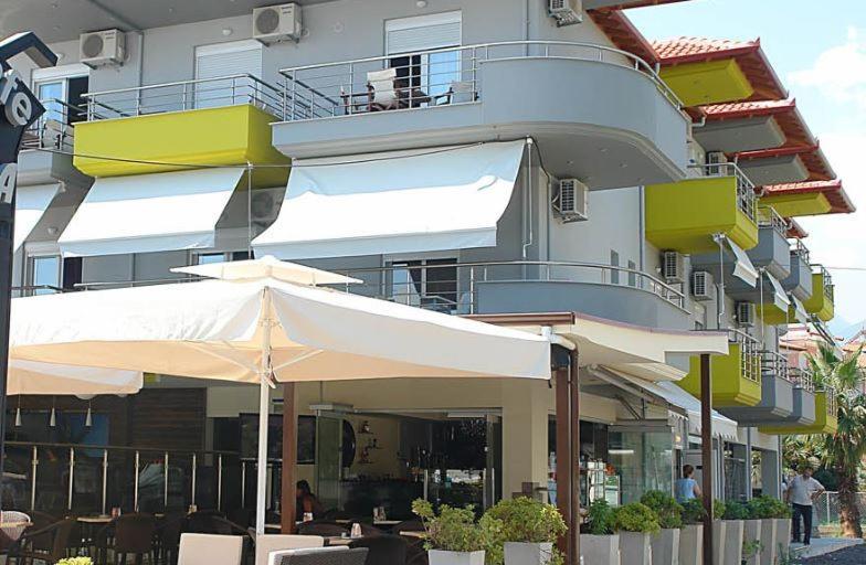 a building with tables and umbrellas in front of it at Klepsidra rooms in Leptokarya