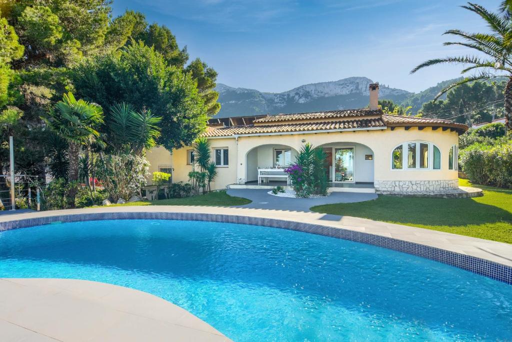 une villa avec une piscine en face d'une maison dans l'établissement Doudou, à Dénia