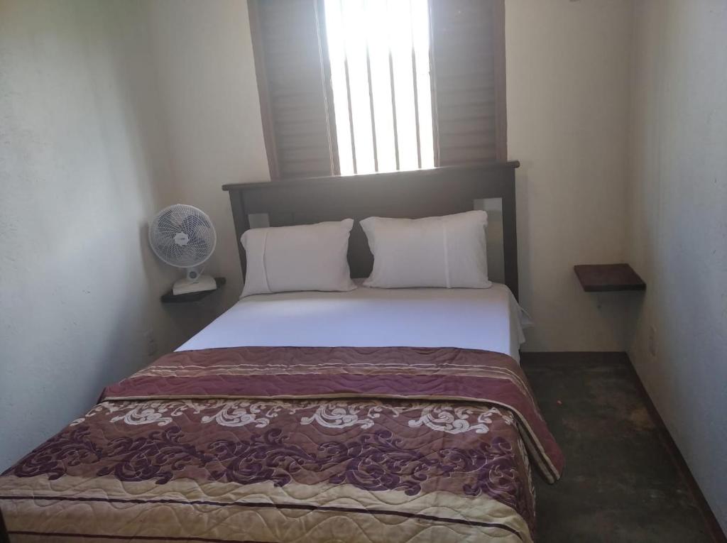 een bed in een kleine kamer met een raam bij Residencial Recanto do Sabiá in Alto Paraíso de Goiás