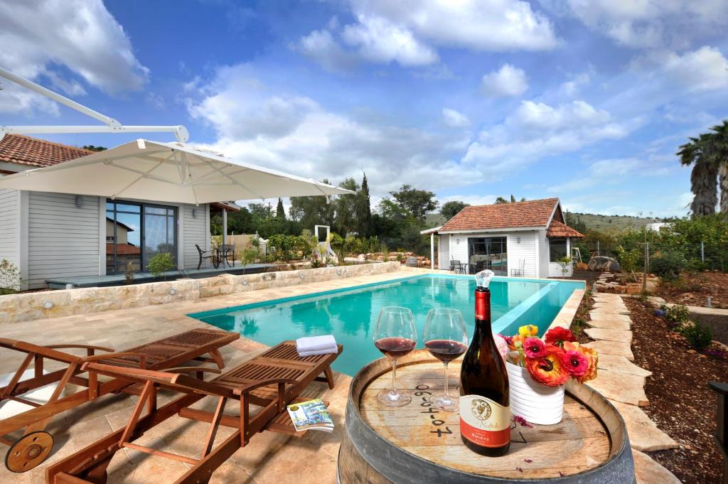 uma piscina com uma mesa com garrafas de vinho e copos em Adilion em Kahal