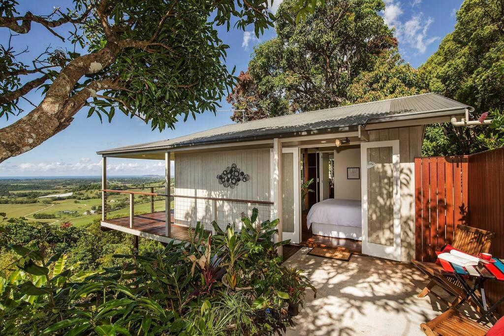 a small guest house with a bed and a balcony at Byron's Secret in Coorabell Creek