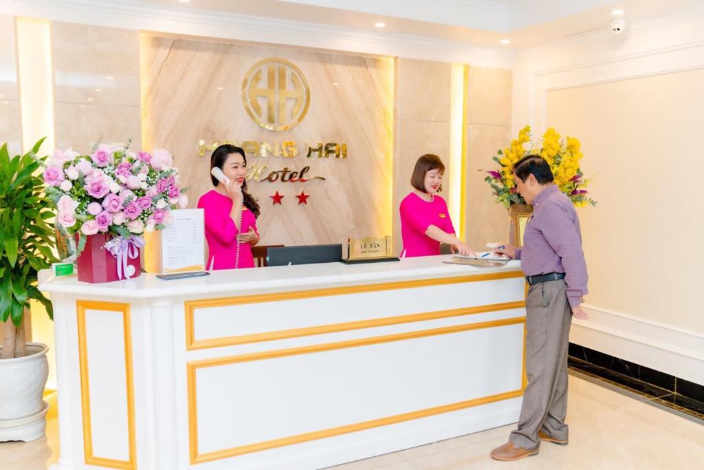 a man standing at a reception desk with two women at Hoang Hai Hotel in Hai Phong