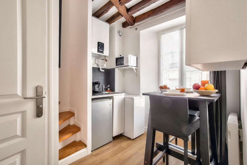 uma cozinha com armários brancos e uma mesa num quarto em Charming Duplex Studio in the heart of Paris em Paris