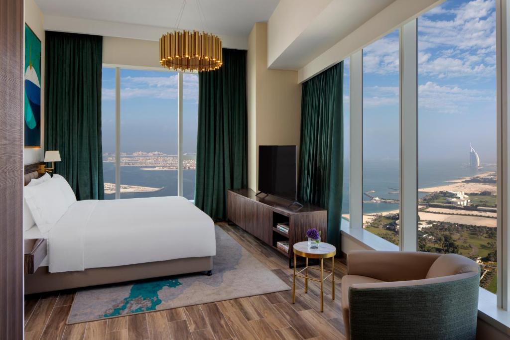 - une chambre avec un lit et de grandes fenêtres dans l'établissement Avani Plus Palm View Dubai Hotel & Suites, à Dubaï