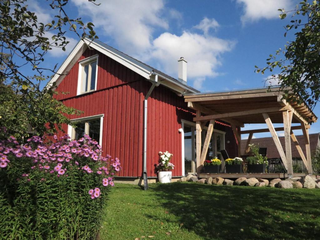 a red barn with a porch and some flowers at Mednieki Kalvene in Krusāti