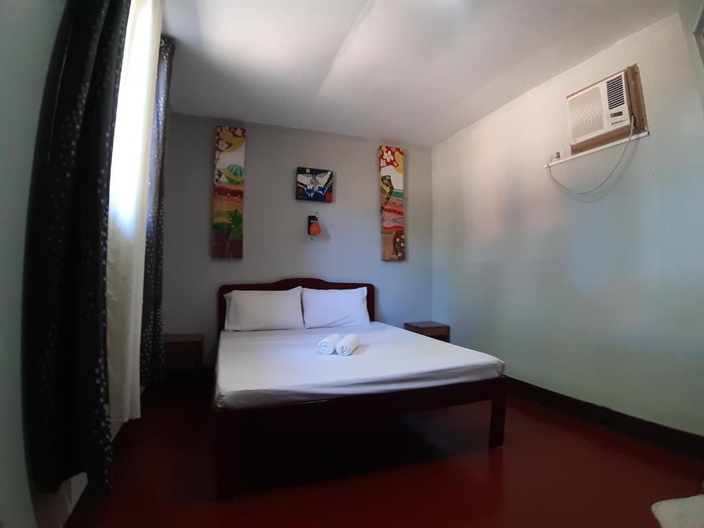 a small bedroom with a white bed in a room at OYO 671 Natua's Cabin in Puerto Princesa City