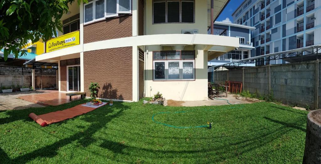 une cour en face d'un bâtiment avec une pelouse verte dans l'établissement Punsuk, à Khon Kaen