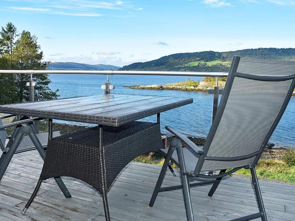 una mesa y una silla en una terraza con vistas al agua en 8 person holiday home in TORVIKBUKT, en Torvikbukt