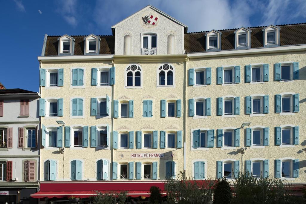 un grand bâtiment blanc avec une horloge en haut dans l'établissement Hôtel de France Contact-Hôtel, à Évian-les-Bains