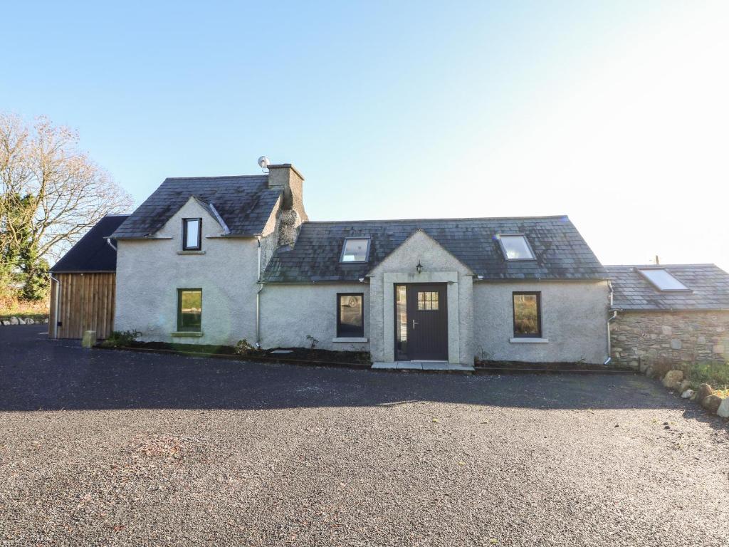 a white house with a black roof and a driveway at Dairy Lane Cottage in Bunclody