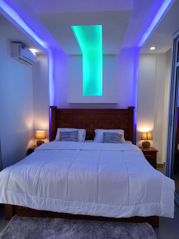 - une chambre avec un grand lit et une lumière verte dans l'établissement Appart MKD Mixta, à Dakar