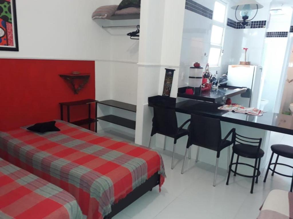 1 dormitorio con cama, escritorio y mesa en Kitnet em Guarujá - Pitangueiras (sem garagem), en Guarujá