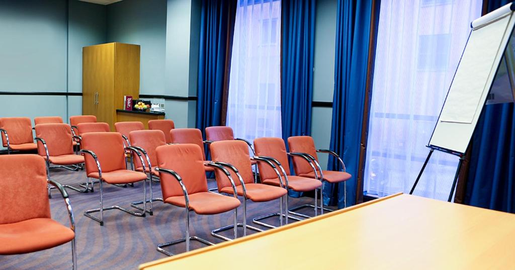 a conference room with orange chairs and a podium at Leonardo Hotel Manchester Central in Manchester