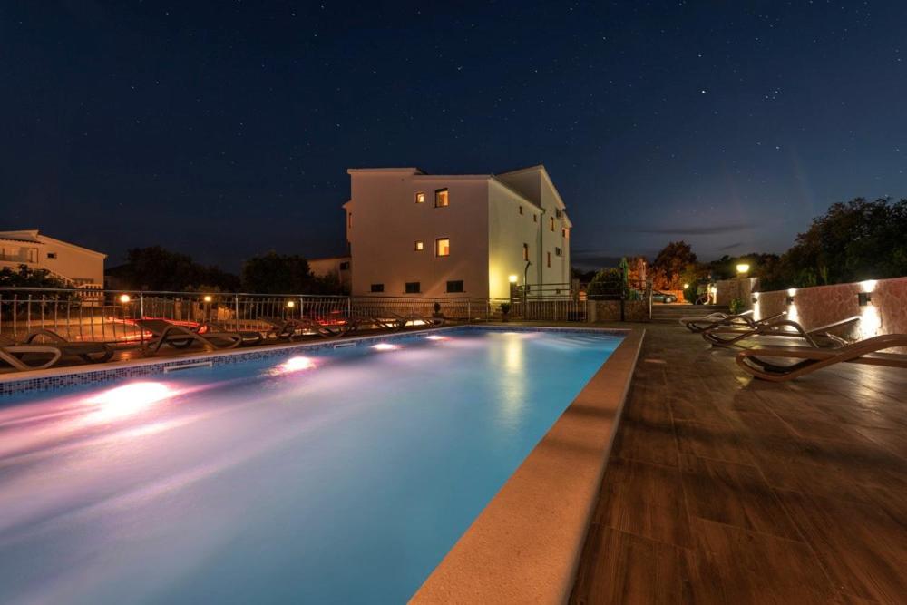 a swimming pool at night in front of a building at Apartments Karen in Vinišće