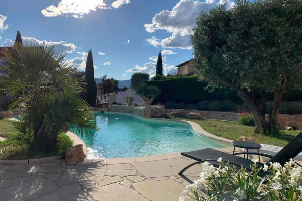 una piscina en un patio con árboles y una casa en Villa des Oliviers avec piscine en Chassagny