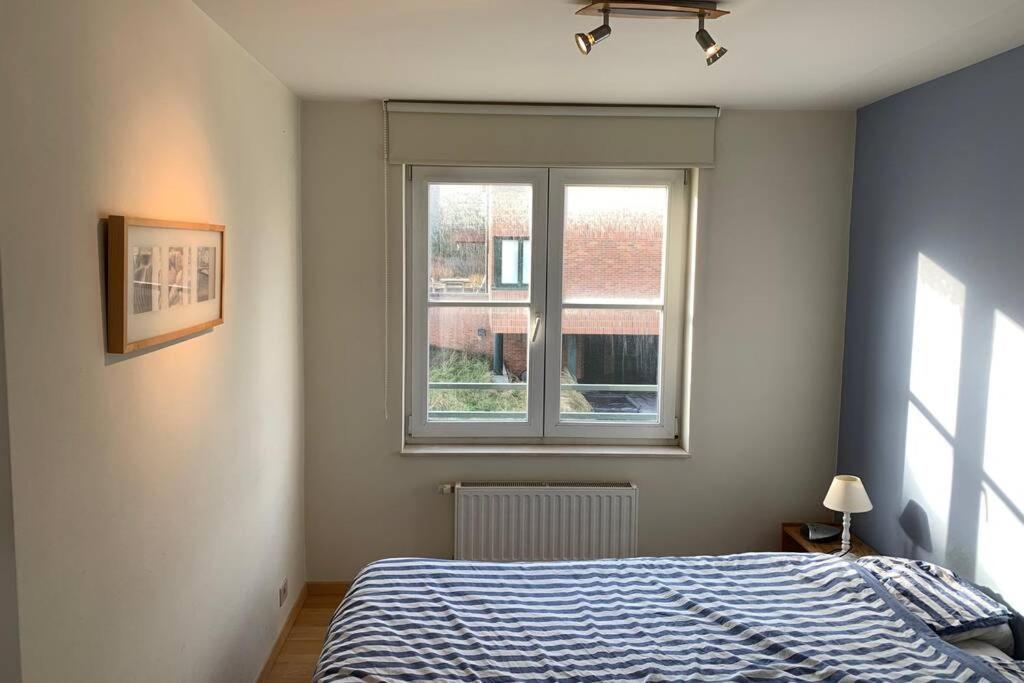 um quarto com uma cama e uma janela em Two bedroom apartment - 50 meters from beach and KYC em Koksijde