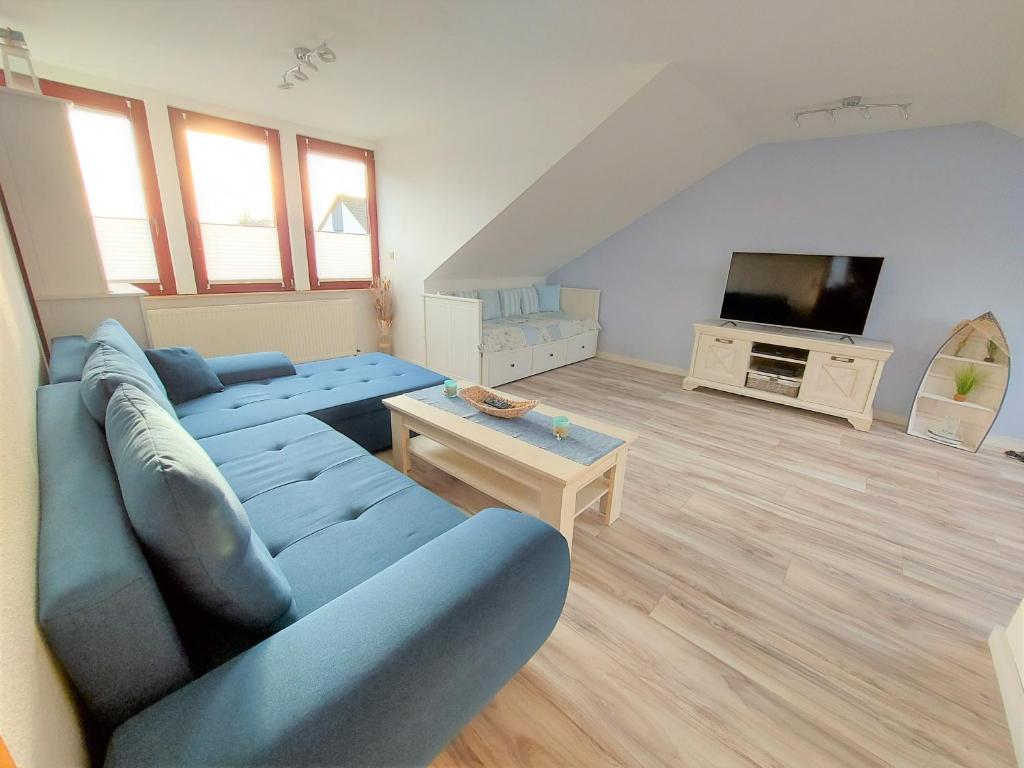 a living room with a blue couch and a tv at Ferienwohnung Seestern 21 in Bremerhaven