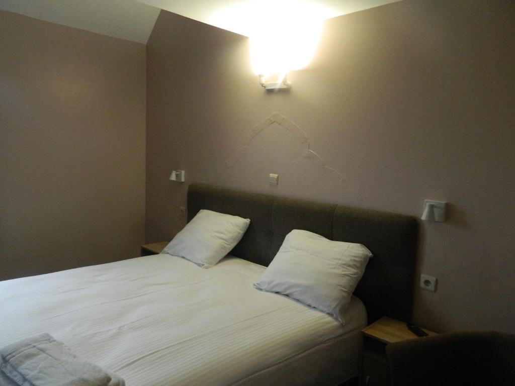 - un lit avec deux oreillers et une lumière sur le mur dans l'établissement at-PACIFIC-HOTEL, à Wavre